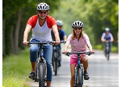Family cycling together on a paved trail with child bike seats and trailers